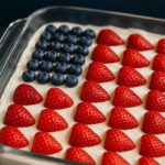 No-Bake Cheesecake Flag Cake topped with fresh strawberries and blueberries, arranged to resemble the American flag.