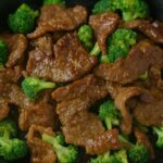 Keto Low Carb Beef and Broccoli stir-fry in a cast-iron skillet, featuring tender beef slices and vibrant broccoli florets coated in a savory, glossy sauce.