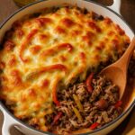 Keto Philly Cheesesteak Casserole with melted cheese, tender beef, bell peppers, and onions baked to perfection in a white skillet.