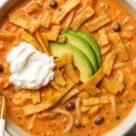 Creamy Chicken Tortilla Soup topped with avocado slices, crispy tortilla strips, and a dollop of sour cream.