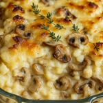 Baked creamy mushroom casserole in a glass dish topped with melted cheese and fresh thyme sprigs.
