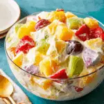 A vibrant bowl of cheesecake fruit salad with strawberries, kiwi, grapes, pineapple, and creamy cheesecake dressing.