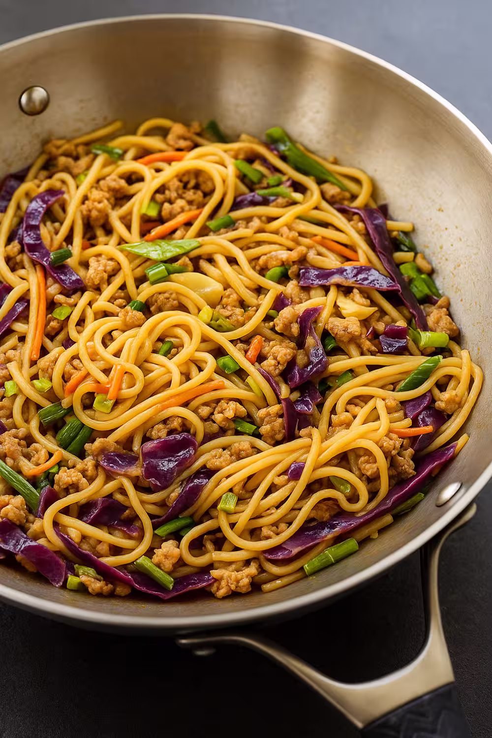 Colorful potsticker noodle bowl with ground meat, cabbage, and vegetables in a skillet
