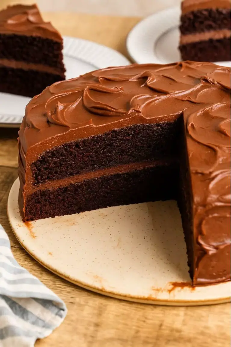 A rich and moist Black Magic Cake with dark chocolate layers and creamy chocolate frosting, with one slice removed.
