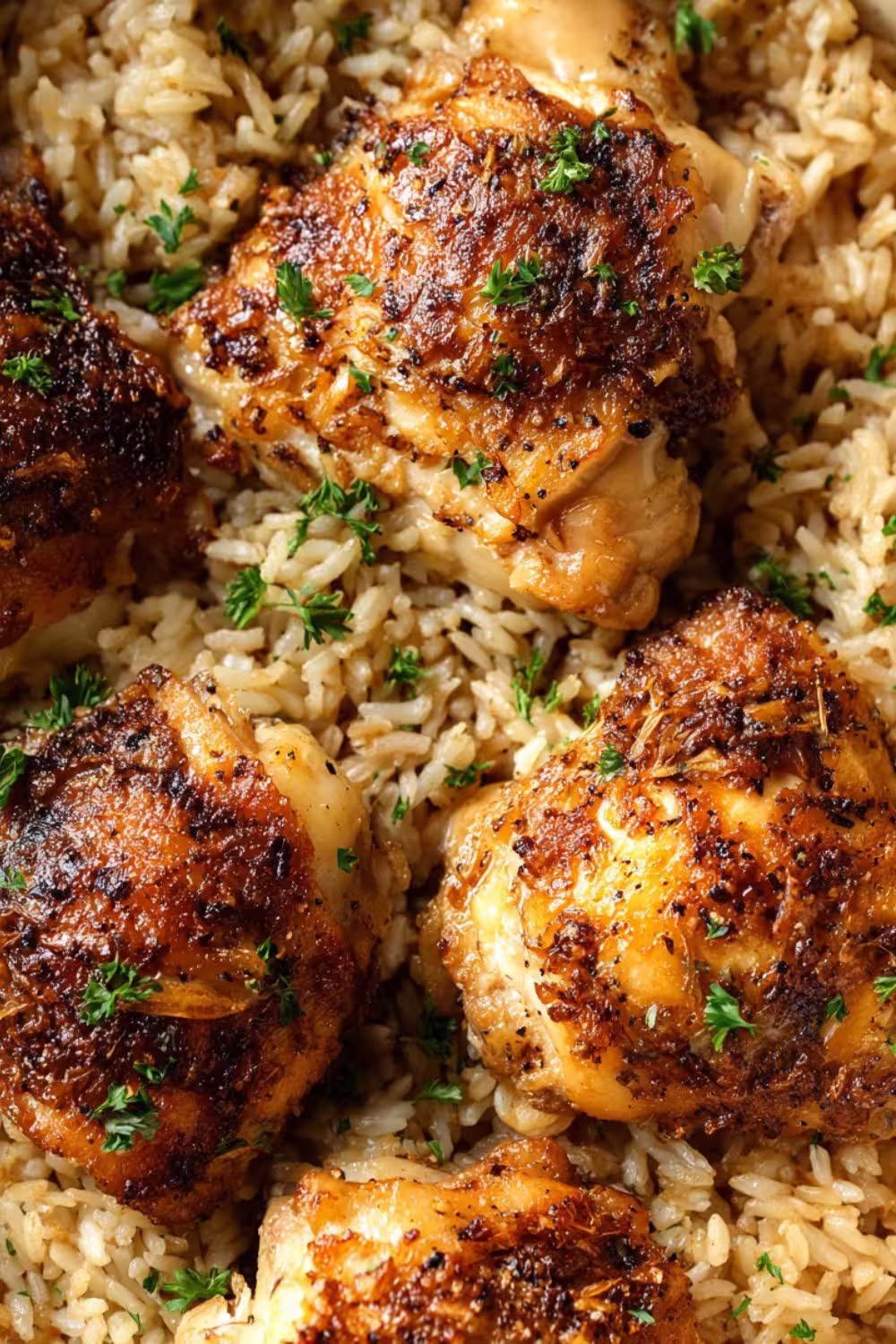 Golden oven-baked chicken thighs served over a bed of seasoned rice, garnished with fresh herbs.