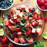 A refreshing bowl of berry watermelon fruit salad with strawberries, blueberries, raspberries, and fresh mint.