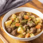 Bowl of beef stew with chunks of beef, potatoes, carrots, and celery in a rich broth.