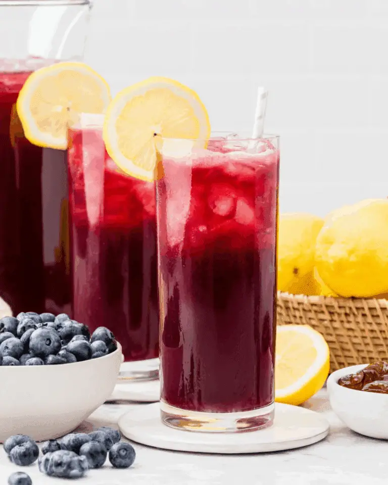 Blueberry Lemonade served in tall glasses with ice, lemon slices, and a deep purple hue from fresh blueberries.
