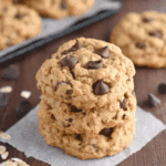 A stack of Brown Butter Pumpkin Oatmeal Chocolate Chip Cookies with visible oats and chocolate chips on a parchment paper.