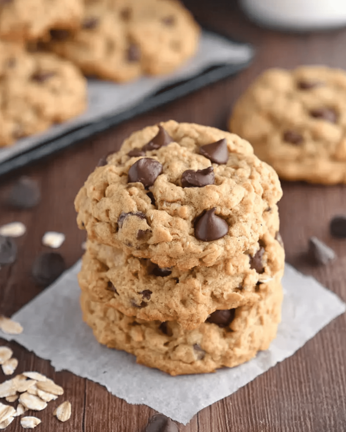 A stack of Brown Butter Pumpkin Oatmeal Chocolate Chip Cookies with visible oats and chocolate chips on a parchment paper.