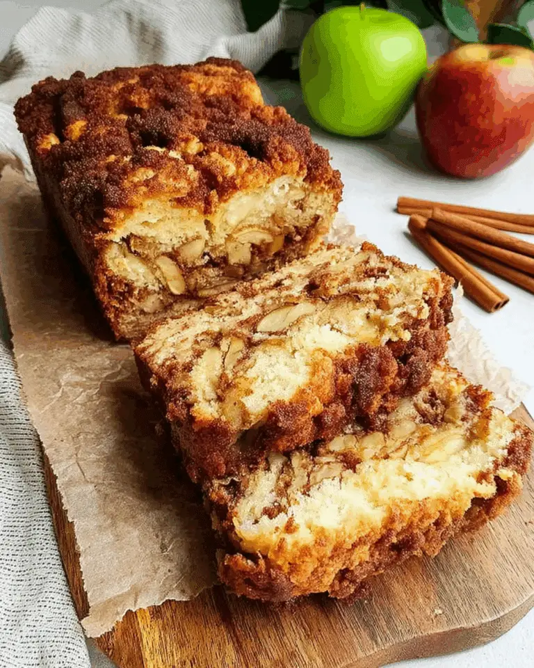 Sliced cinnamon apple bread with a golden-brown crust and visible apple chunks and cinnamon swirls.