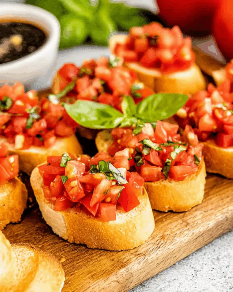Classic Italian bruschetta topped with diced tomatoes and fresh basil on toasted baguette slices, served on a wooden board.