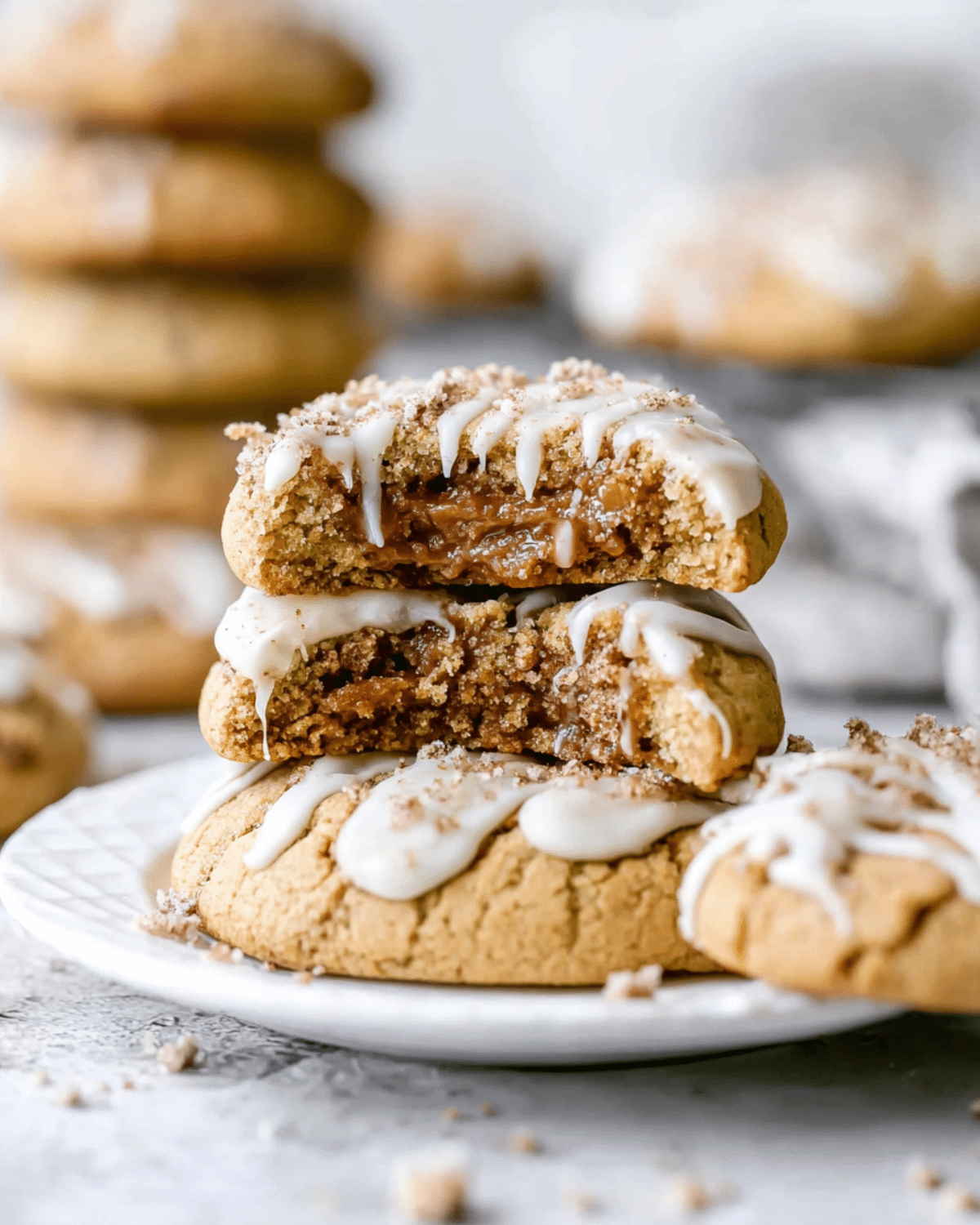 A stack of Coffee Cake Cookies filled with a gooey cinnamon center, topped with white icing drizzle and crumbly streusel.