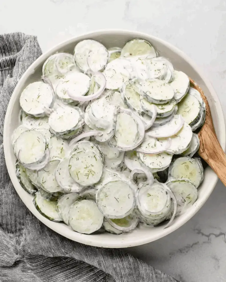 Bowl of creamy cucumber salad with thinly sliced cucumbers, red onions, and a dill yogurt dressing.