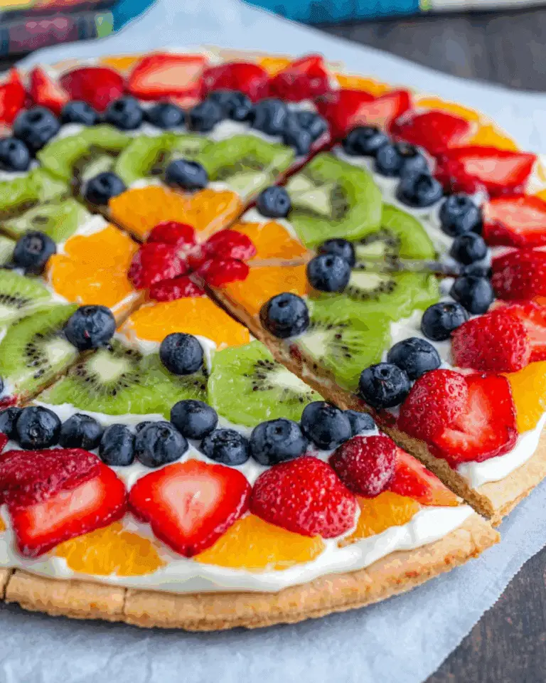 Easy fruit and cracker pizza topped with sliced strawberries, kiwi, blueberries, oranges, and cream on a cookie crust.