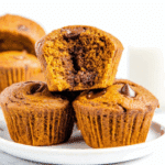 Flourless pumpkin muffin with a gooey chocolate center stacked on a white plate.