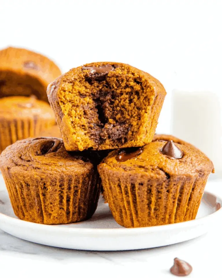 Flourless pumpkin muffin with a gooey chocolate center stacked on a white plate.