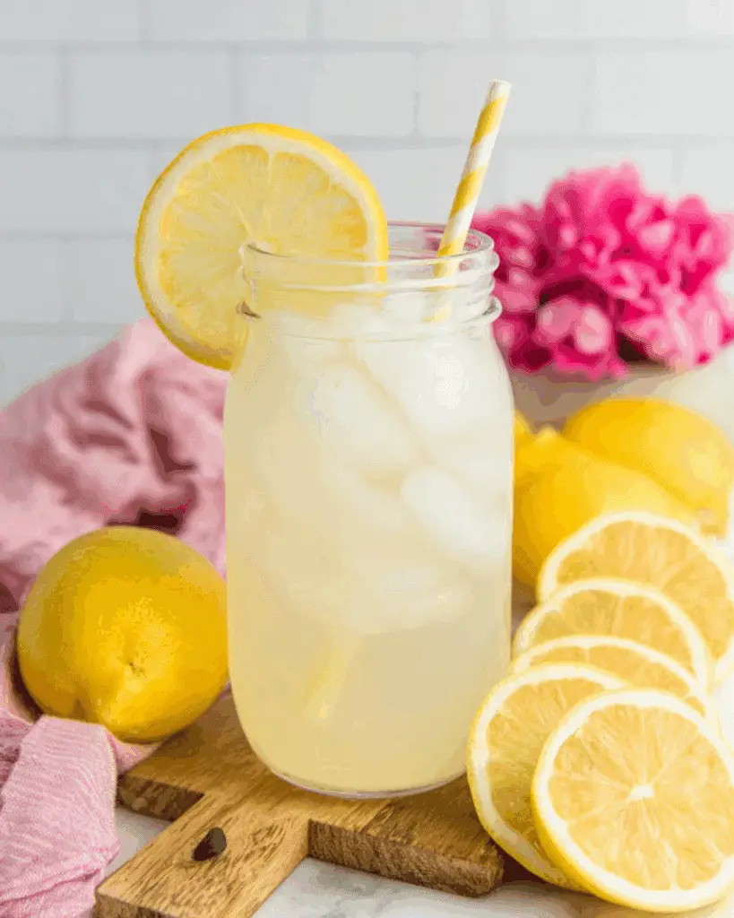Freshly Squeezed Lemonade in a mason jar with ice, a lemon slice garnish, and a yellow-striped straw.