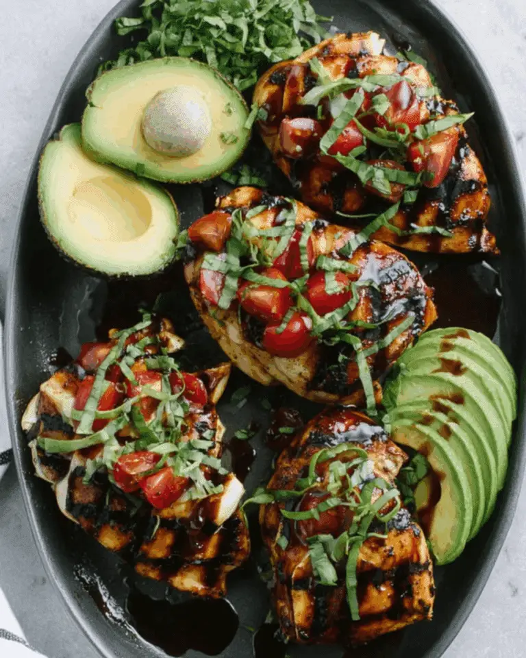 Grilled California avocado chicken topped with cherry tomatoes, basil, and balsamic glaze, served with fresh avocado halves.