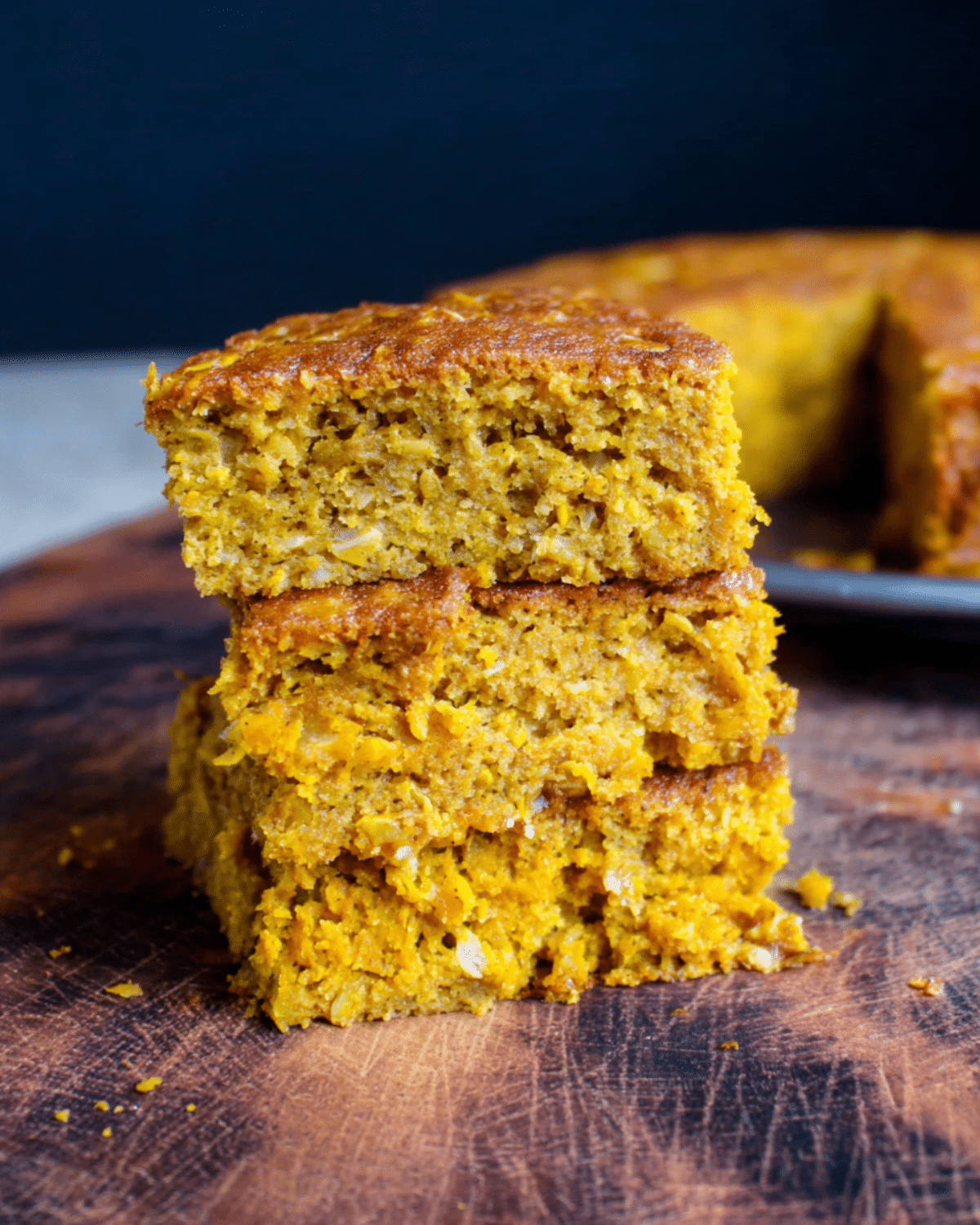 Stacked slices of healthy pumpkin oatmeal breakfast cake on a wooden board, showing moist and dense texture.