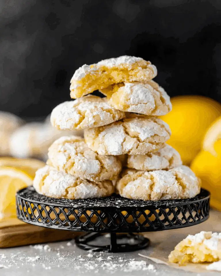 Lemon crinkle cookies stacked on a black wire stand, coated in powdered sugar with a soft, cracked surface.