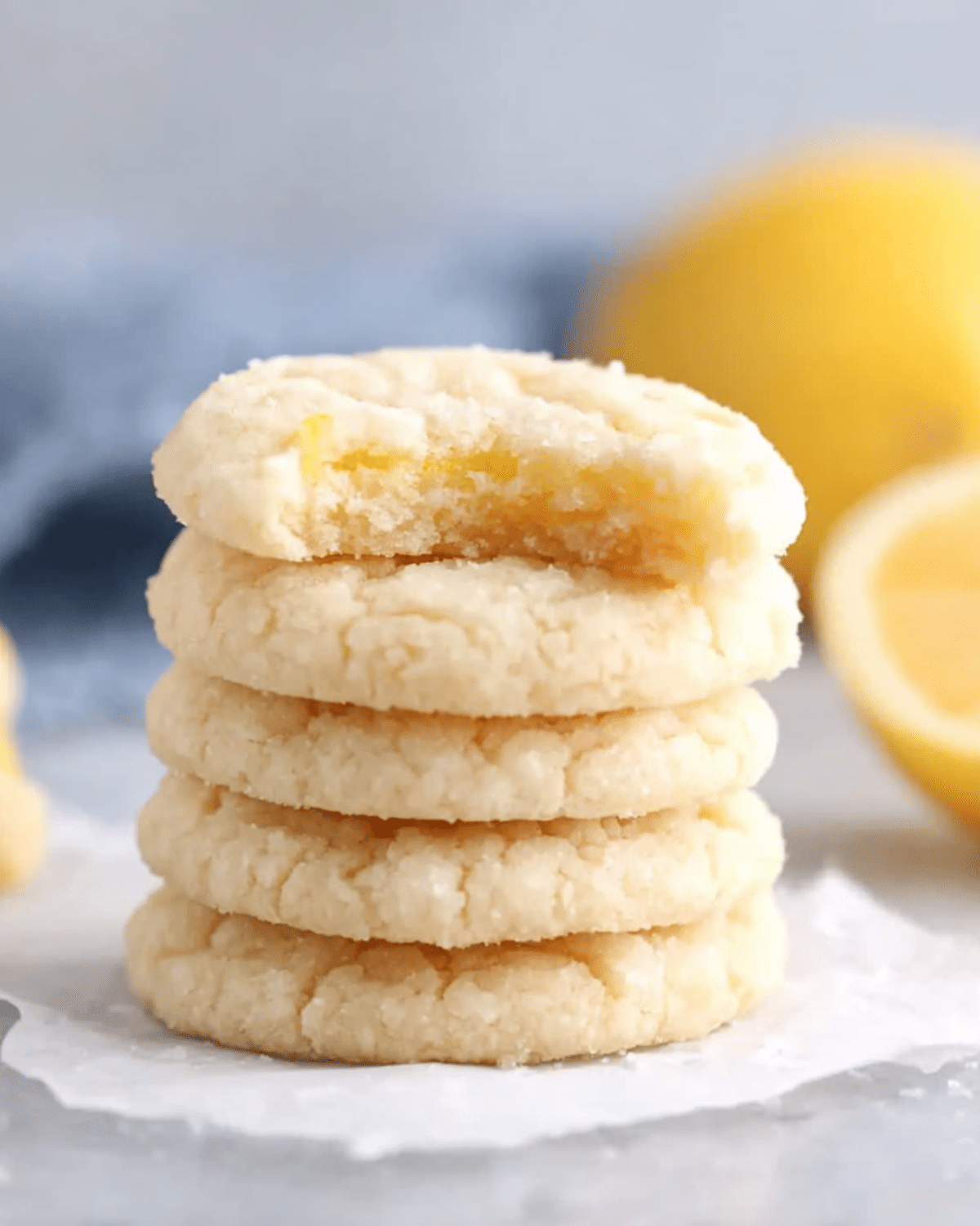 Stack of soft Lemon Sugar Cookies with a bite taken out of the top cookie