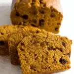 Slices of no added sugar pumpkin banana bread with a moist, dense texture and studded with raisins.