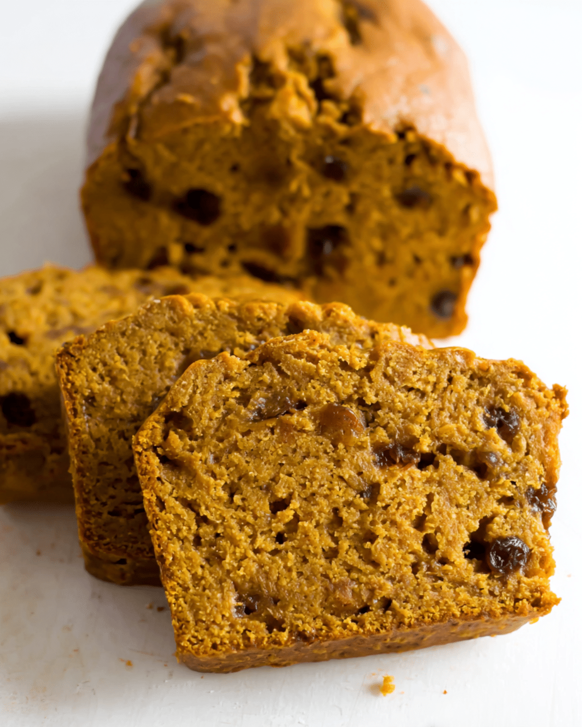 Slices of no added sugar pumpkin banana bread with a moist, dense texture and studded with raisins.