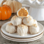 No-Bake Pumpkin Pie Bites stacked on a white plate, coated in white chocolate and topped with graham cracker crumbs.