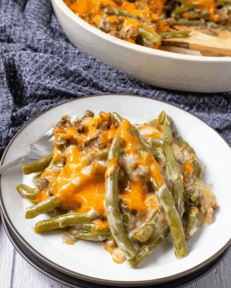 Paula Deen's Southern Green Bean Casserole served on a plate, topped with melted cheddar cheese.