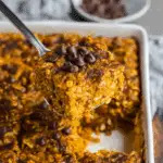 A square of pumpkin baked oatmeal topped with chocolate chips being lifted from a baking dish.