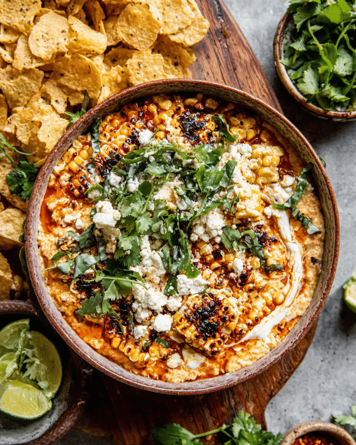 Bowl of quick elote-inspired corn dip topped with charred corn, crumbled cheese, cilantro, and served with tortilla chips.