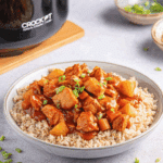 Sweet Hawaiian Crockpot Chicken served over brown rice and garnished with chopped green onions.