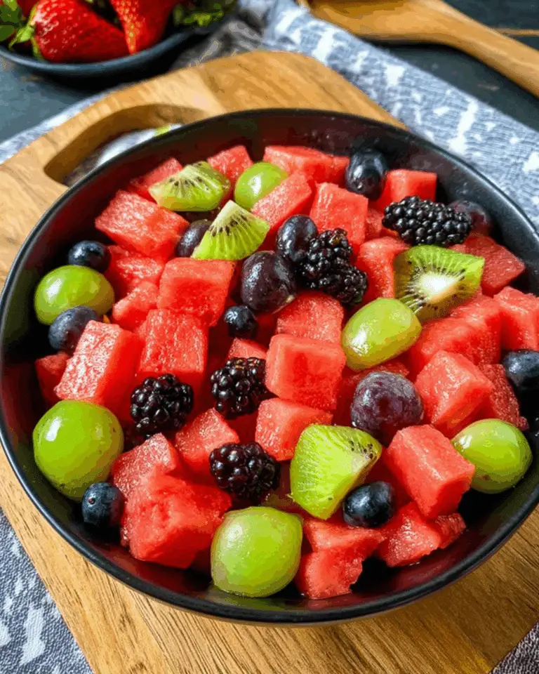Bowl of watermelon fruit salad with cubes of watermelon, green grapes, kiwi slices, blackberries, blueberries, and red grapes.
