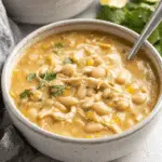 Bowl of white chicken chili with white beans, shredded chicken, corn, and garnished with cilantro.