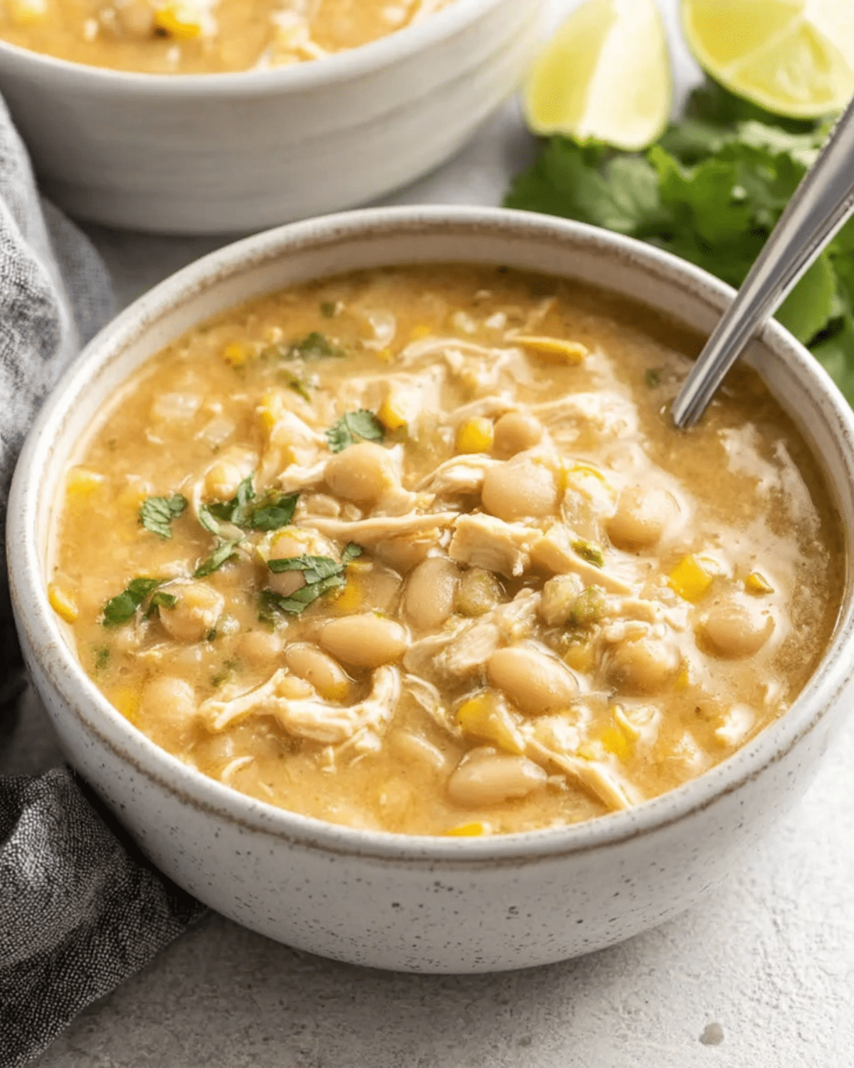 Bowl of white chicken chili with white beans, shredded chicken, corn, and garnished with cilantro.