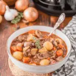 A bowl of Witch’s Cauldron Beef Stew filled with chunks of beef, baby potatoes, mushrooms, carrots, and herbs in a rich broth.