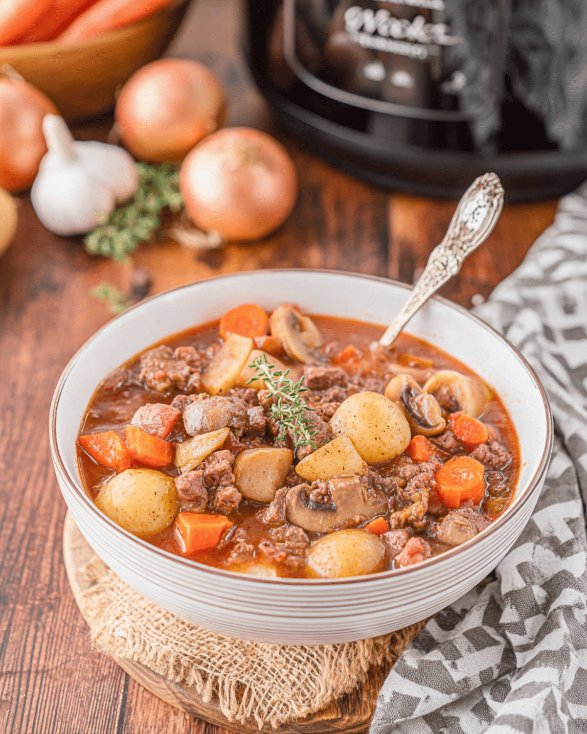 A bowl of Witch’s Cauldron Beef Stew filled with chunks of beef, baby potatoes, mushrooms, carrots, and herbs in a rich broth.