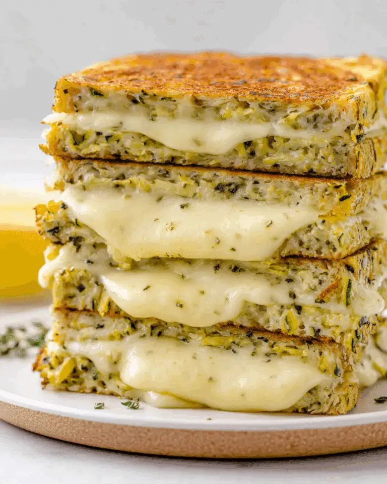 Stack of zucchini grilled cheese sandwiches with melted cheese oozing out.