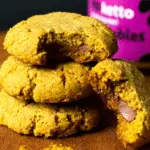 Stack of 3 ingredient keto pumpkin cookies with one broken open to reveal a soft, chocolatey center.