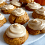 Soft Amish pumpkin cookies with frosting neatly arranged on a white plate.