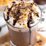 Glass mug filled with Baileys Hot Chocolate topped with whipped cream, chocolate shavings, caramel drizzle, and chocolate syrup.
