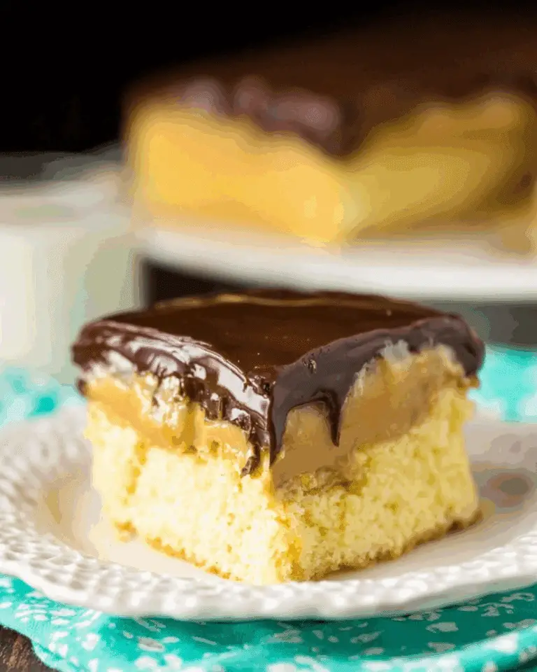 A slice of Boston Cream Poke Cake with yellow cake, creamy custard filling, and rich chocolate ganache topping.