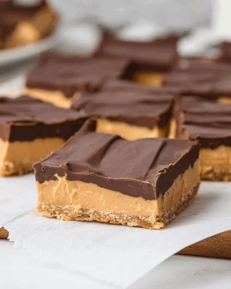 Close-up of a buckeye bar with a graham cracker crust, creamy peanut butter filling, and a smooth chocolate topping.