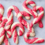 Candy cane cookies with red and white twisted dough, sprinkled with red sugar and crushed peppermint.