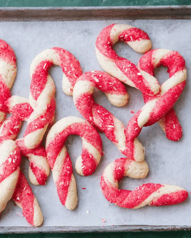 Candy cane cookies with red and white twisted dough, sprinkled with red sugar and crushed peppermint.