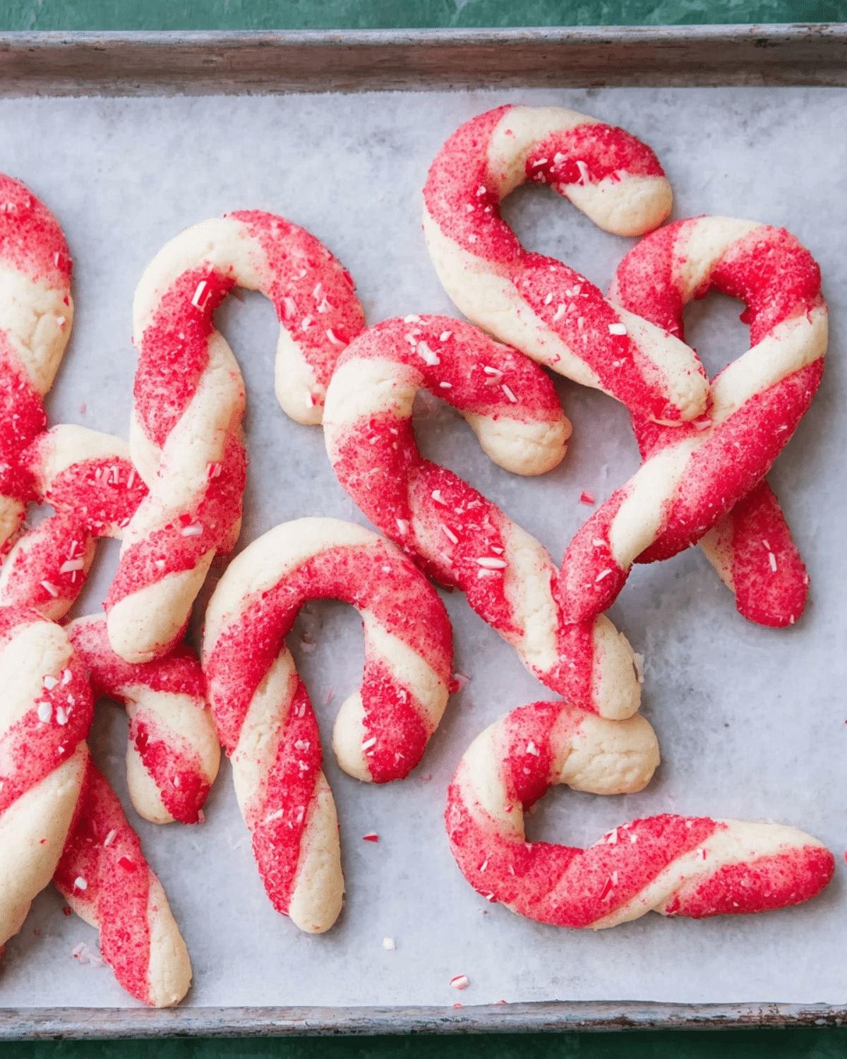 Candy cane cookies with red and white twisted dough, sprinkled with red sugar and crushed peppermint.