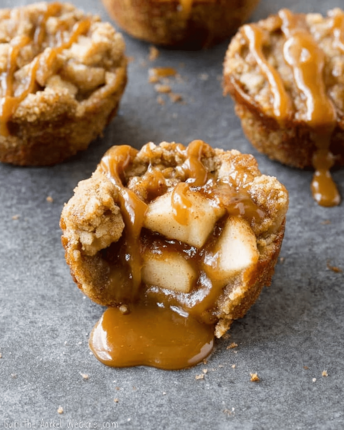 Caramel apple cup filled with cinnamon-spiced apple chunks, topped with streusel and drizzled with caramel sauce, with caramel oozing out.
