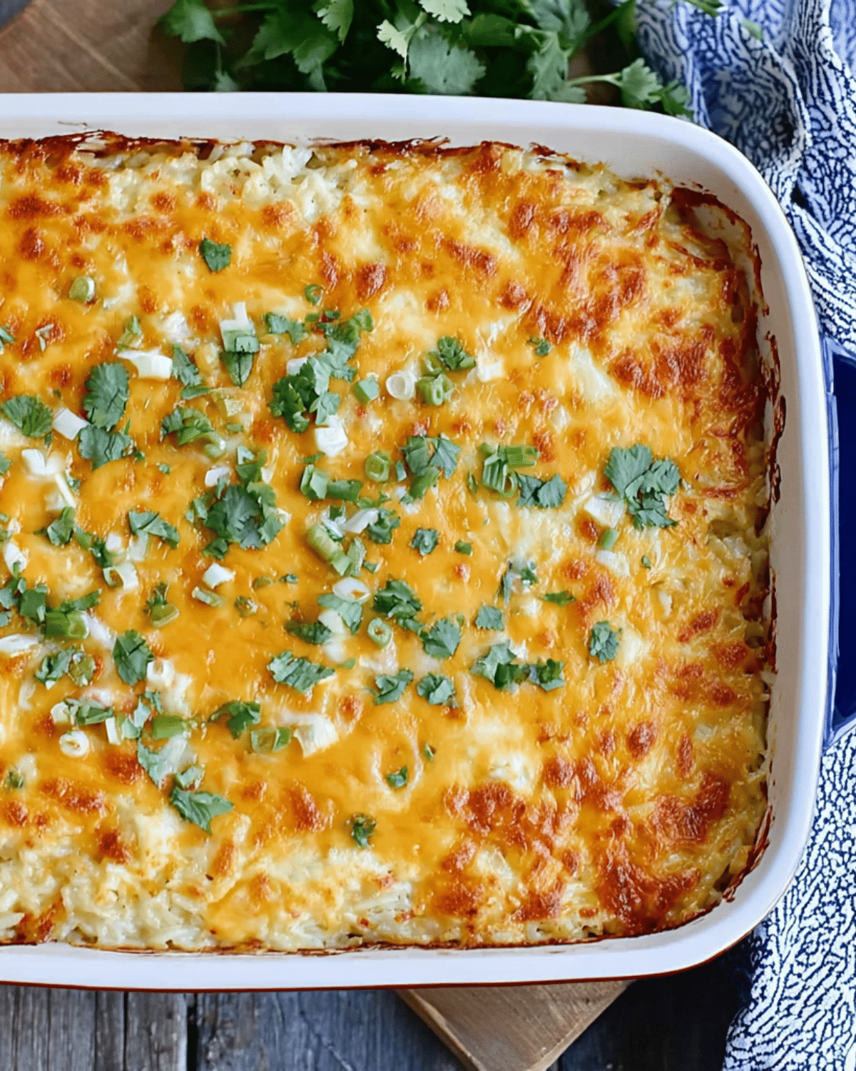 Baked Cheesy Green Chile Rice Casserole topped with melted golden cheese, fresh cilantro, and green onions in a casserole dish.