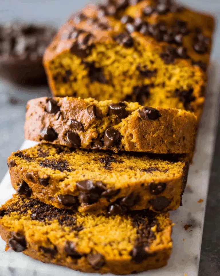 Sliced chocolate chip pumpkin bread with rich chocolate chips throughout, displayed on a marble surface.